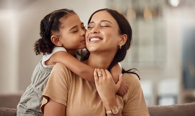 A daughter embracing her mother, both smiling.