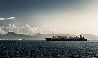 A large cargo ship wtih dome-shaped containers sailing across a vast body of water.