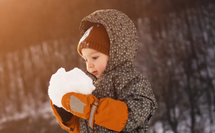 A baby playing in the snow.