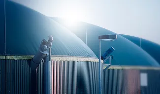 Rows of large, blue, domed storage tanks under a hazy sky.
