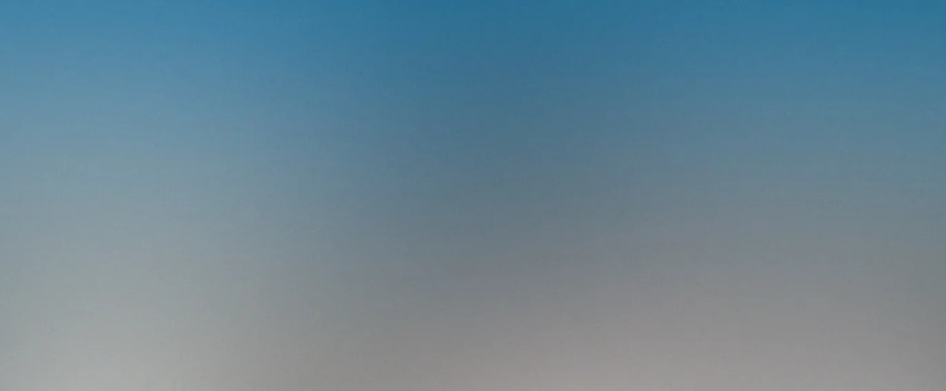 Large blue pipelines supported by a dark metal structure against a clear blue sky.