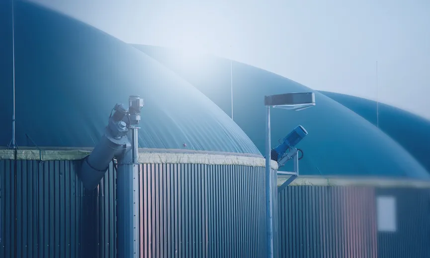 Rows of large, blue, domed storage tanks under a hazy sky.